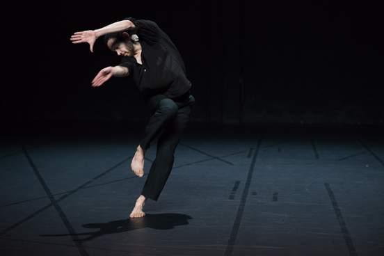 One dancer tilts sideways in motion, one leg lifted and arms raised, with expressive hands.